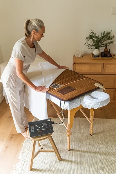 Functional Medicine Toms River NJ Practitioner Setting Up Biomat A practitioner setting up a biomat on a therapeutic massage table before a patient's appointment